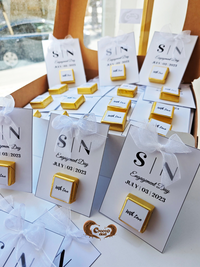 Gold and white jewelry boxes with 'SIN' branding on a table.