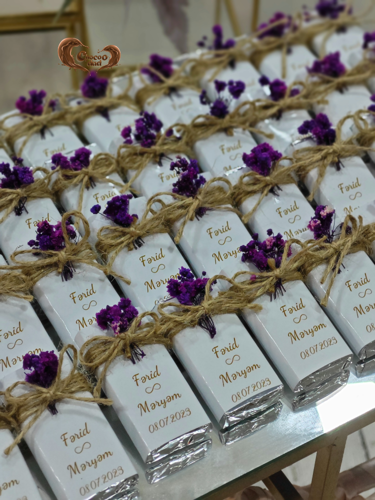 White chocolate bars with gold text and purple flowers on a marble surface
