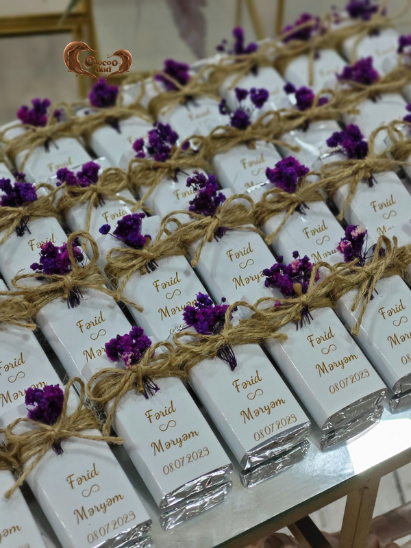 White chocolate bars with gold text and purple flowers on a marble surface