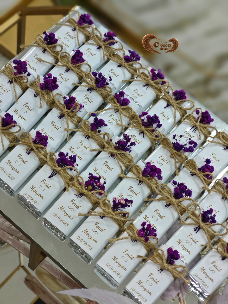White boxes with purple flowers and twine packaging on a decorative stand.