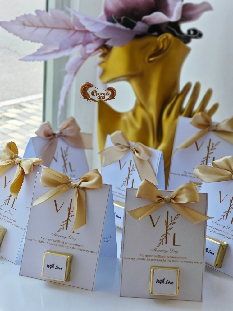 Decorative boxes with gold ribbons and a blurred background of a person wearing a yellow dress and pink headband.