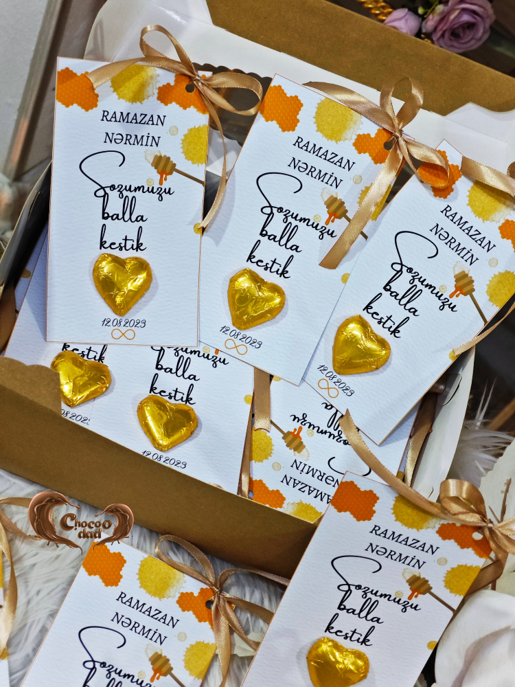 Gold heart-shaped chocolates with white packaging featuring text and decorative ribbons.