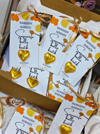 Gold heart-shaped chocolates with white packaging featuring text and decorative ribbons.