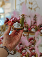 Hand holding a small decorative item with blurred floral background