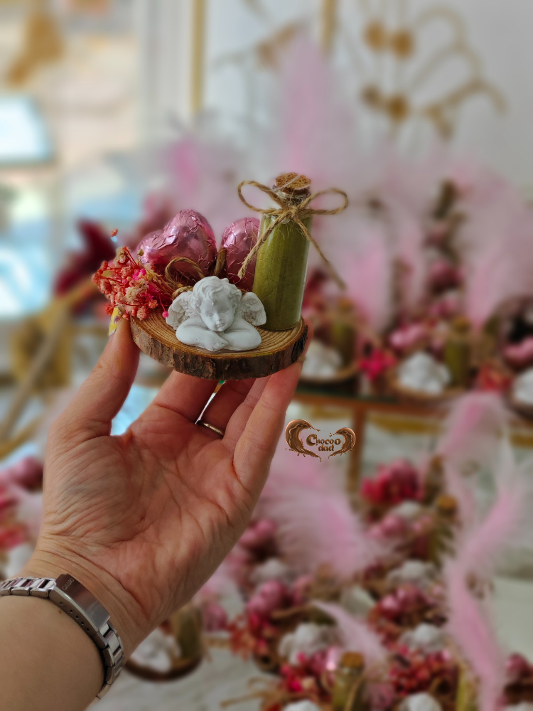 Hand holding a small decorative item with blurred floral background