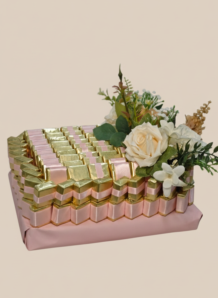 Packaged chocolates with pink and gold ribbons and flowers on a beige background
