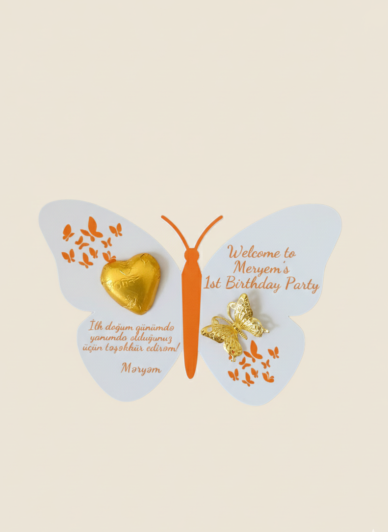 Butterfly-shaped party favor with gold heart, wings, and text on a beige background
