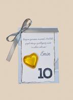 Gift box with a gold heart and ribbon on a beige background