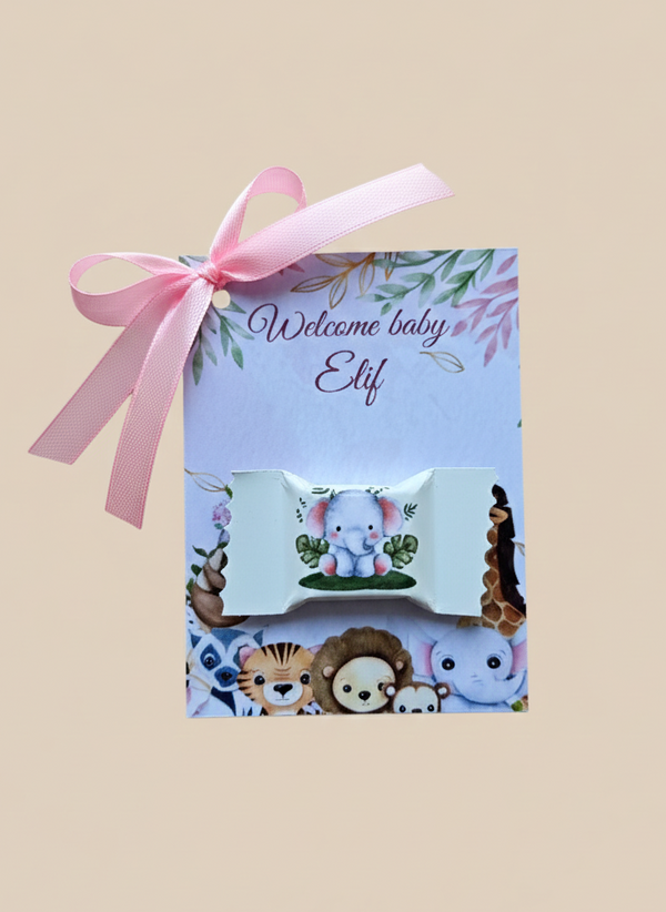 Baby shower gift set with pink ribbon and personalized card on a beige background