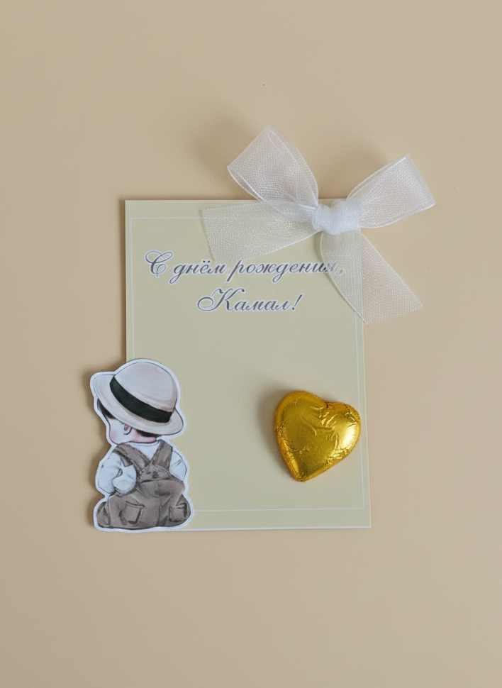 Card with a small figurine and gold heart-shaped object on a beige background