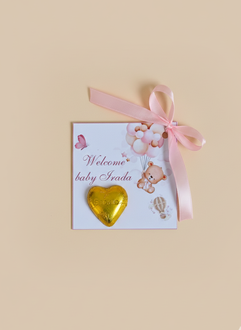 Baby shower card with gold heart, teddy bear, and pink ribbon on a beige background