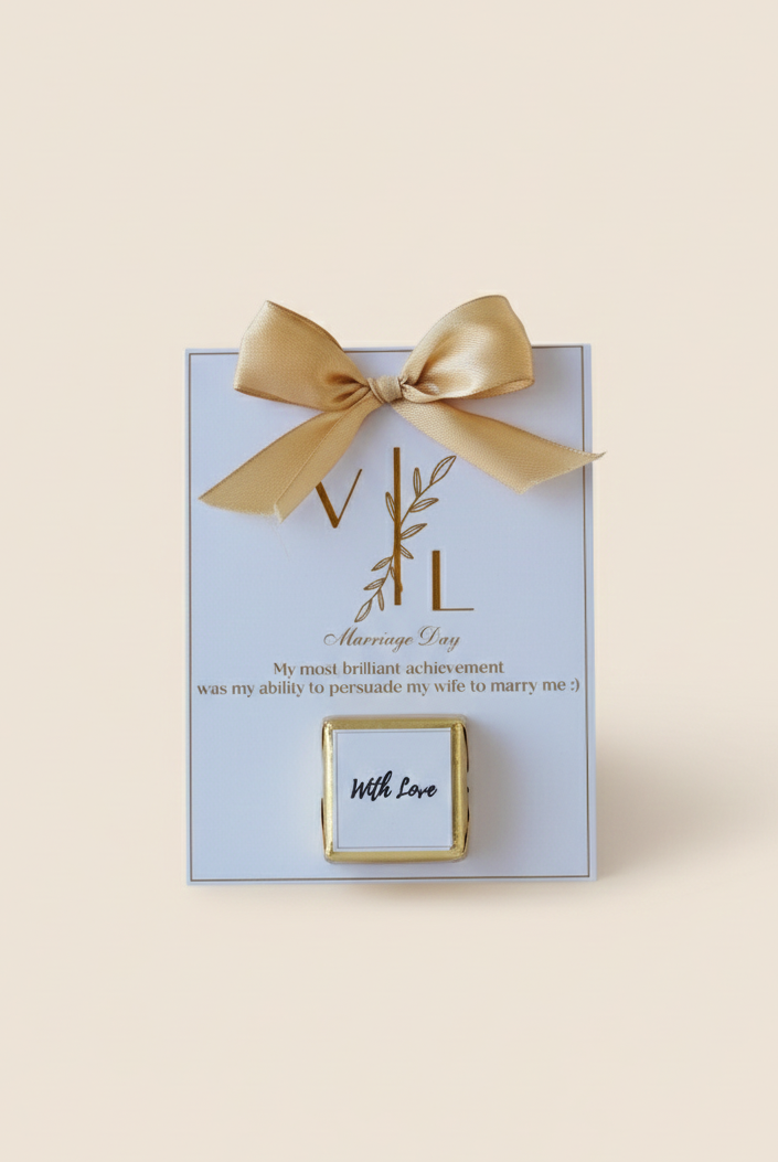 Gold jewelry box with 'WL' initials on a light blue card with a gold bow.