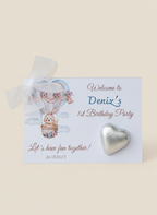 Invitation card for Deniz's 1st birthday party with a heart-shaped candy on a beige background