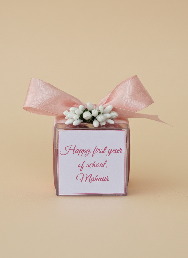 Gift box with pink ribbon and floral decoration on a beige background