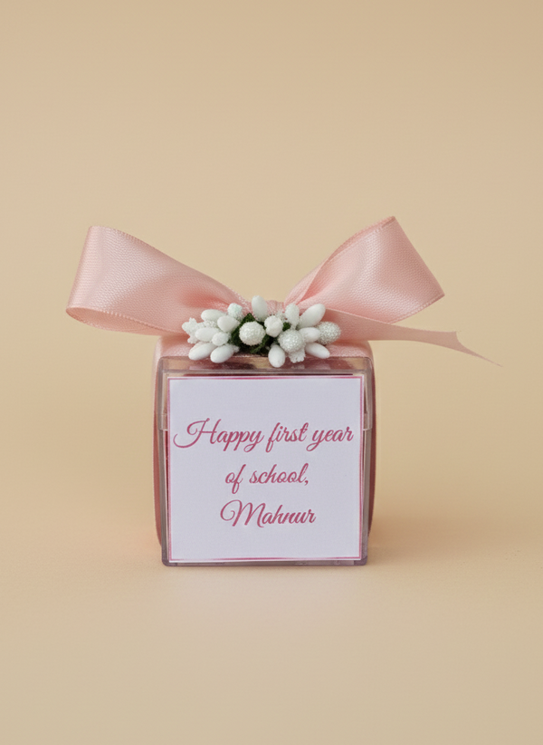 Gift box with pink ribbon and floral decoration on a beige background