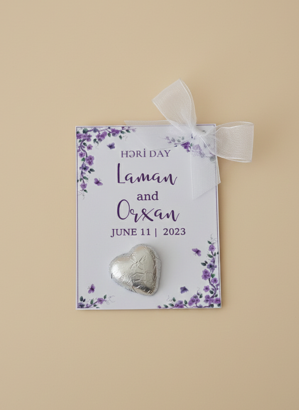 Heart-shaped silver pin on a floral card with personalized text on a beige background