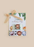 Birthday party invitation with animal illustrations and a gold ribbon on a beige background