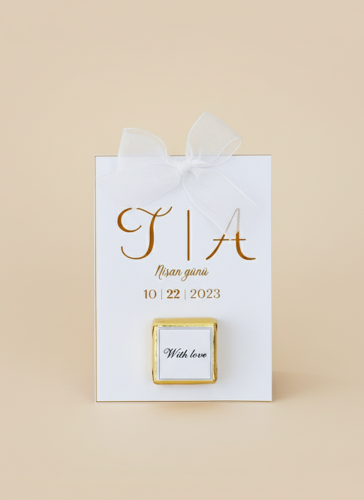 White gift bag with gold text and a small square card on a beige background
