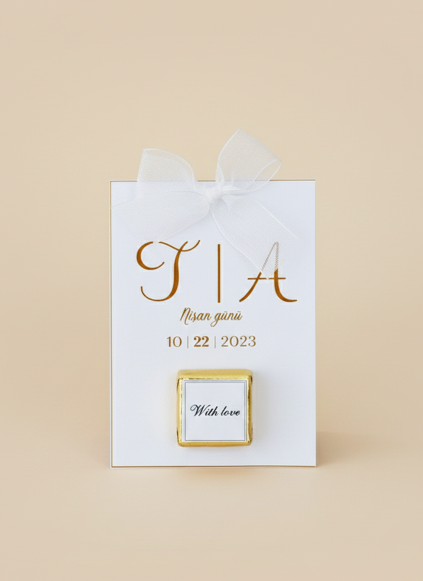 White gift bag with gold text and a small square card on a beige background