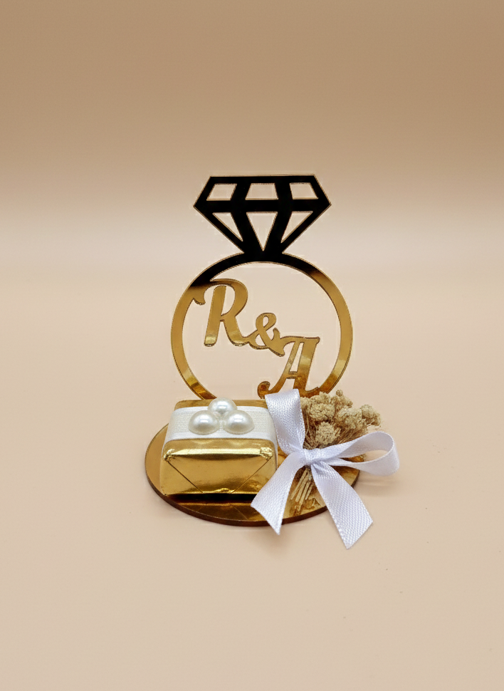 Decorative cake topper with 'R&A' on a beige background and chocolate, engagement chocolate favours
