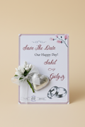 Save the Date card with wedding rings and flowers on a beige background