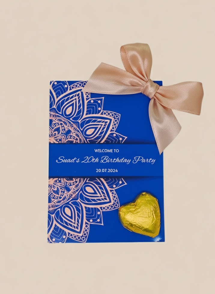 Blue party favor box with decorative bow and gold heart-shaped candy on a beige background