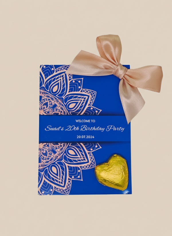 Blue party favor box with decorative bow and gold heart-shaped candy on a beige background