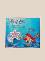 Mermaid-themed party favor with 'Thank You' card on a beige background