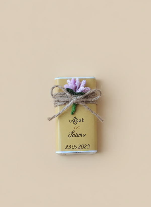 Small rectangular chocolate gift box with floral decoration and string on a beige background