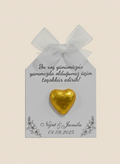 Gold heart-shaped chocolate on a decorative card with text and a bow.