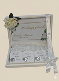 Decorative box with heart-shaped name cards and floral elements on a beige background