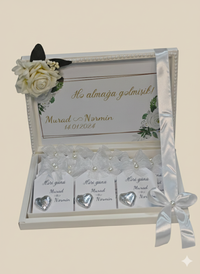 Decorative box with heart-shaped name cards and floral elements on a beige background