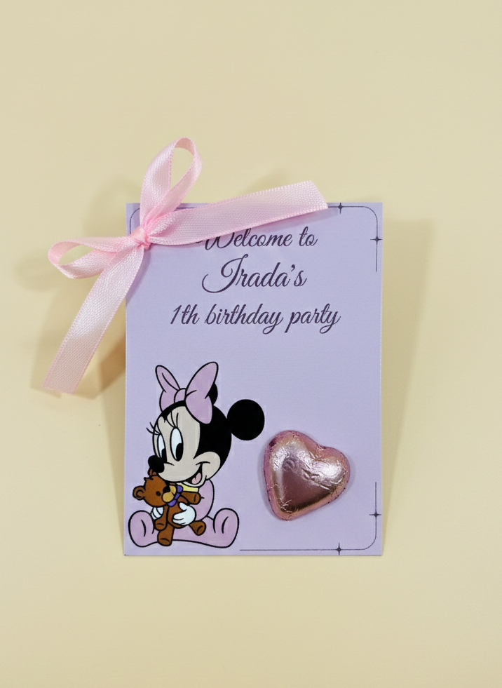 Heart-shaped pin with Minnie Mouse design on a birthday party invitation card with pink ribbon.