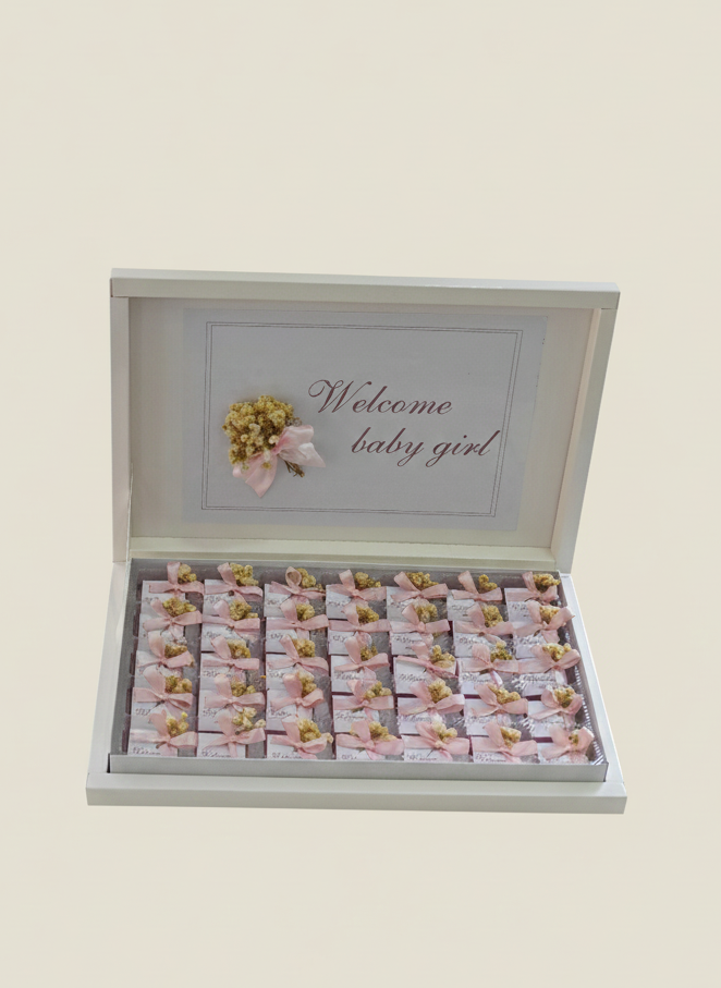 Gift box with baby shower-themed items on a beige background