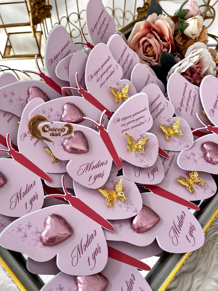 Decorative heart-shaped cards with butterflies and text on a decorative stand.