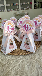 Triangular favor boxes with 'Ahu' text and pink ribbons on a textured surface.