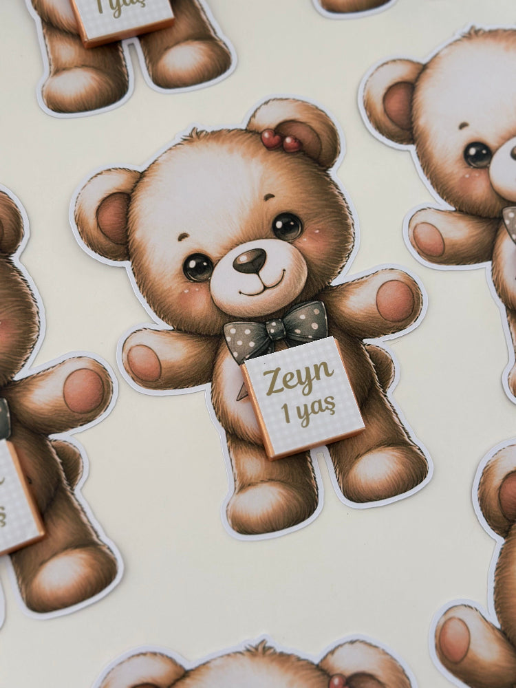 Sticker of a teddy bear holding a sign with 'Zeyn 1yas' on a beige background.