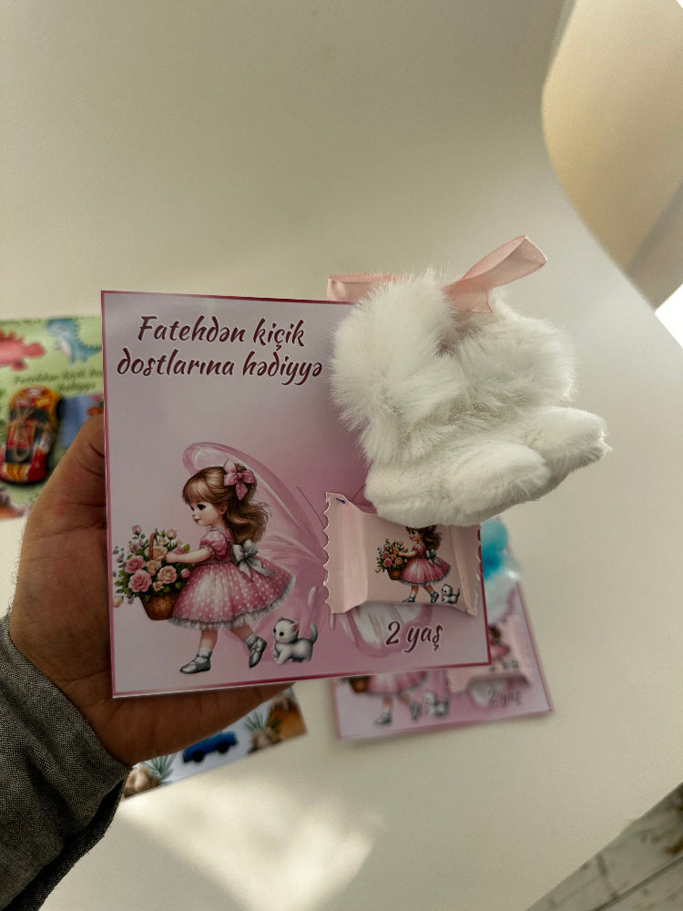 Card with a cartoon character and fluffy white paw held by a hand on a light surface.