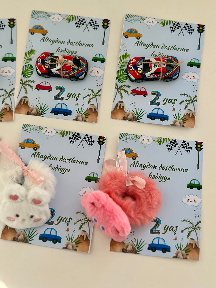 Four children's cards with colorful car designs and two plush toys on a light background.
