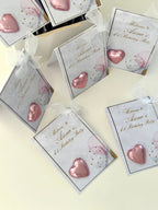 Pink heart-shaped favors with birthday party cards on a light background