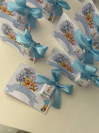 Small boxes with blue ribbons and Winnie the Pooh designs on a light surface