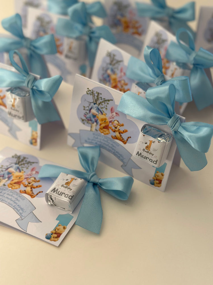 Small boxes with blue ribbons and baby-themed designs on a light background