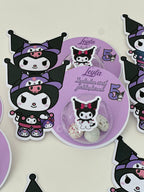 Circular purple product with cartoon cat design surrounded by similar stickers on a light background