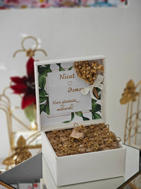 Decorative box with gold elements and a card inside, on a white surface.
