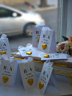 Small gift bags with 'BA' initials and heart decorations on a decorative table.