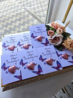 Invitations with heart and butterfly designs on a decorative box with flowers.