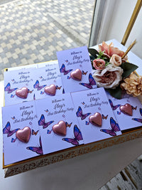 Invitations with heart and butterfly designs on a decorative box with flowers.
