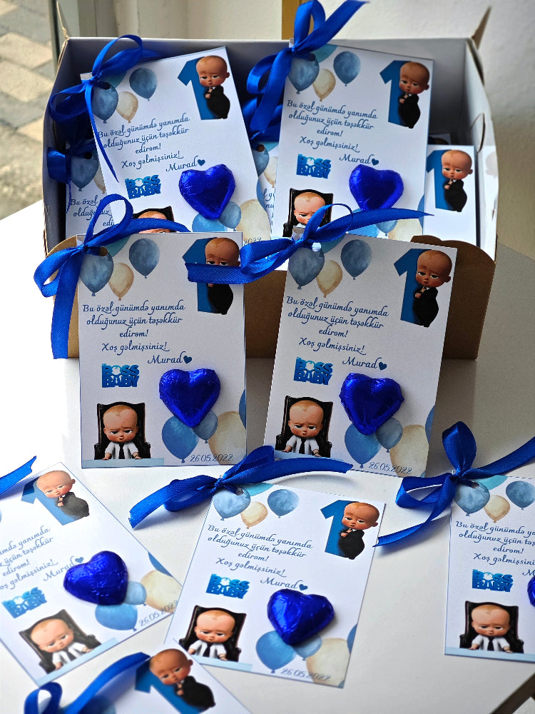 Invitations with blue ribbons and baby pictures on a white surface