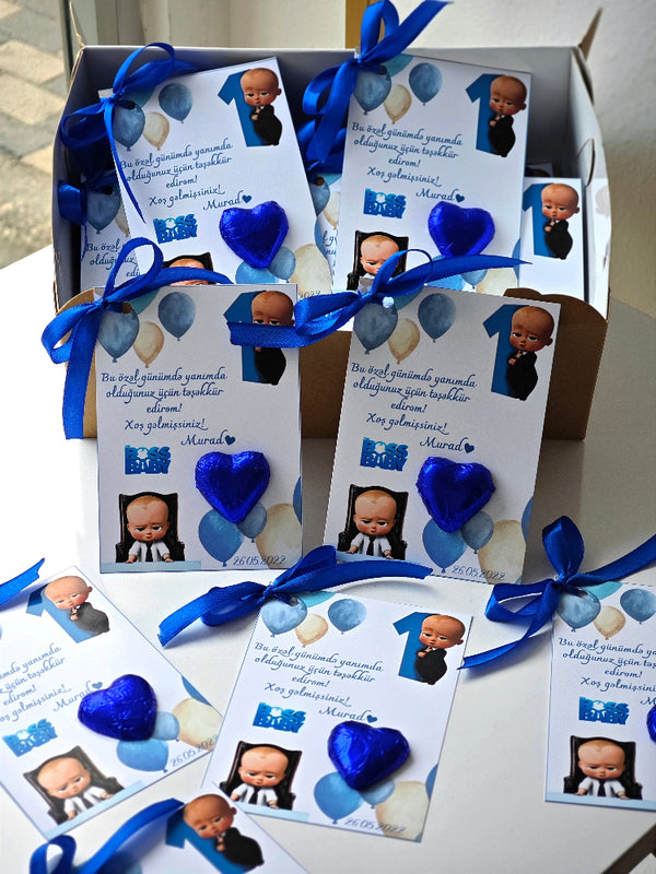 Invitations with blue ribbons and baby pictures on a white surface