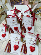 Favor bags with red ribbons and heart-shaped decorations on a decorative surface.